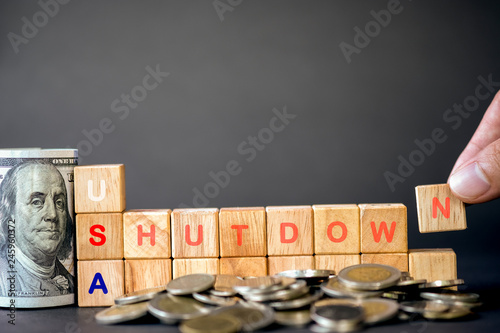 Принти на полотні Human hand putting USA shutdown wording on wooden cubes and US dollar banknote and coins on black background