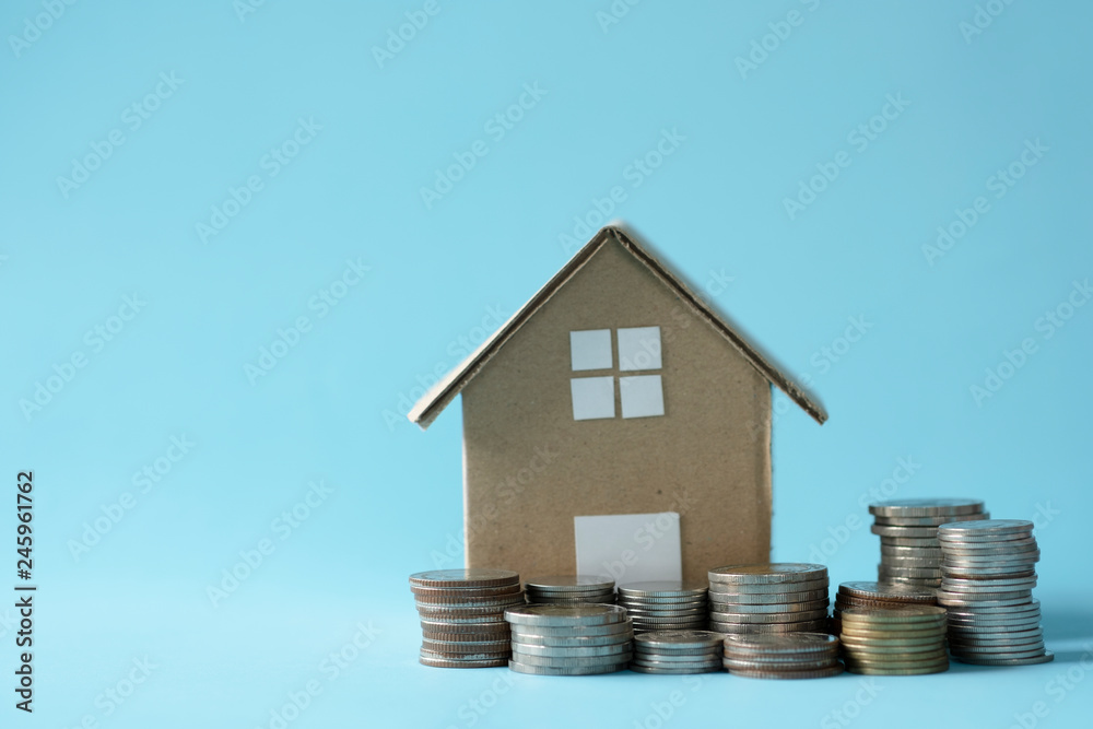 House model around with stacking coins money on blue background. Saving and investment to real estate concept. -image. House model around with stacking coins money on blue background. Saving and investment to real estate concept. -image.
