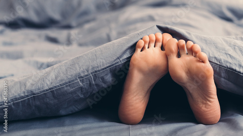 Female beautiful feet under blanket in bed © Prostock-studio