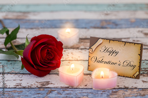 Greeting card with Happy Valentine's Day text, single red rose, and candle lights darker