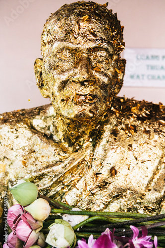 Gold leaf applied for good luck and blessings, covers the sculpture of a venerated Buddhist monk. photo