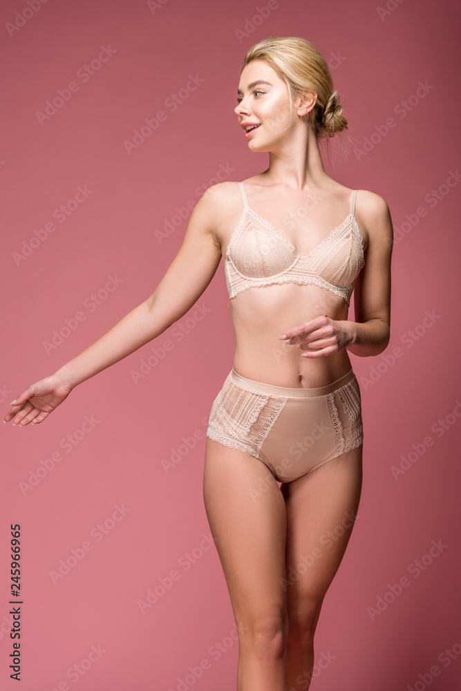 Naklejka premium attractive happy girl posing in lingerie, isolated on pink