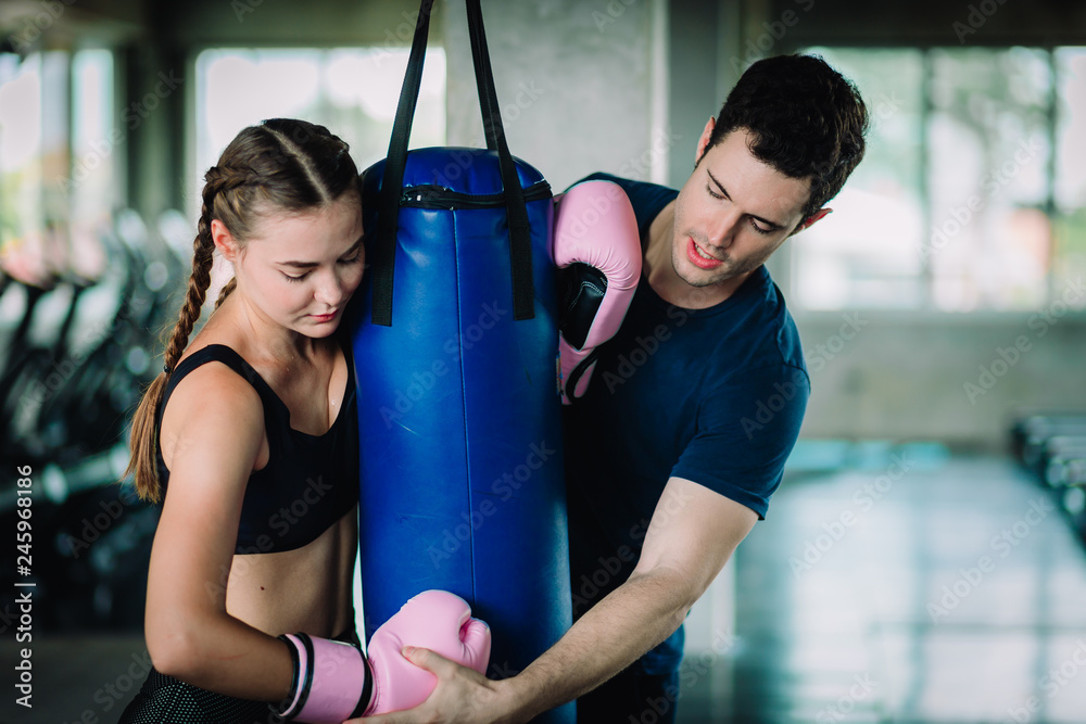 Fit beautiful woman boxer hitting a huge punching bag exercise class in a gym. Boxer woman making direct hit dynamic movement. Healthy, sport, lifestyle, Fitness, workout concept. With copy space.
