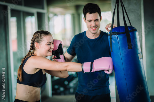 Fit beautiful woman boxer hitting a huge punching bag exercise class in a gym. Boxer woman making direct hit dynamic movement. Healthy, sport, lifestyle, Fitness, workout concept. With copy space. © Shutter B