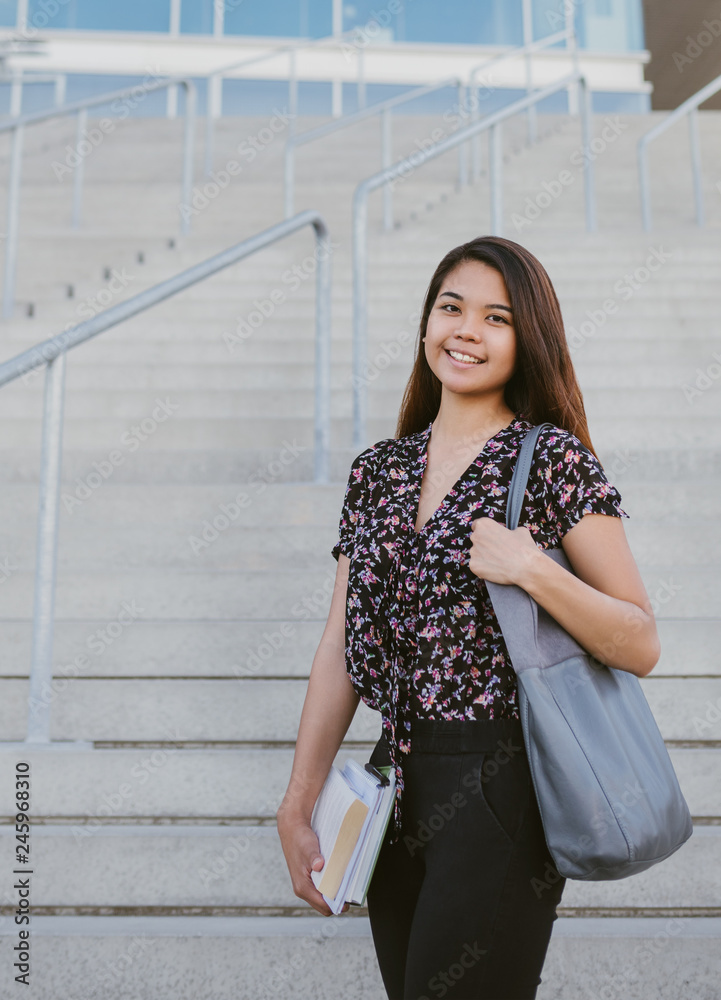 Fototapeta premium Content young Asian university student standing by campus stairs