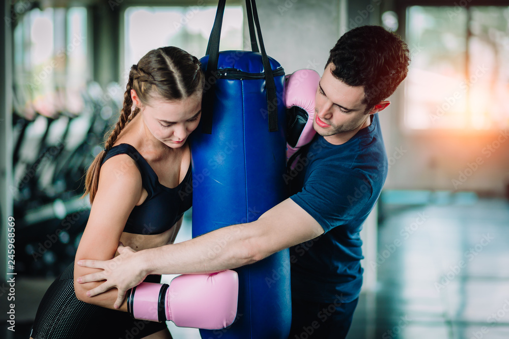 Fit beautiful woman boxer hitting a huge punching bag exercise class in a gym. Boxer woman making direct hit dynamic movement. Healthy, sport, lifestyle, Fitness, workout concept. With copy space.