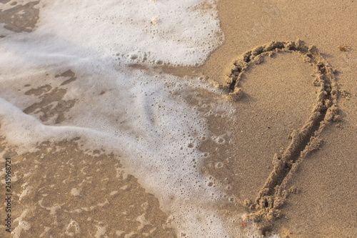  Heart on the Sand in the Beach Being Washed Away by a Wave.