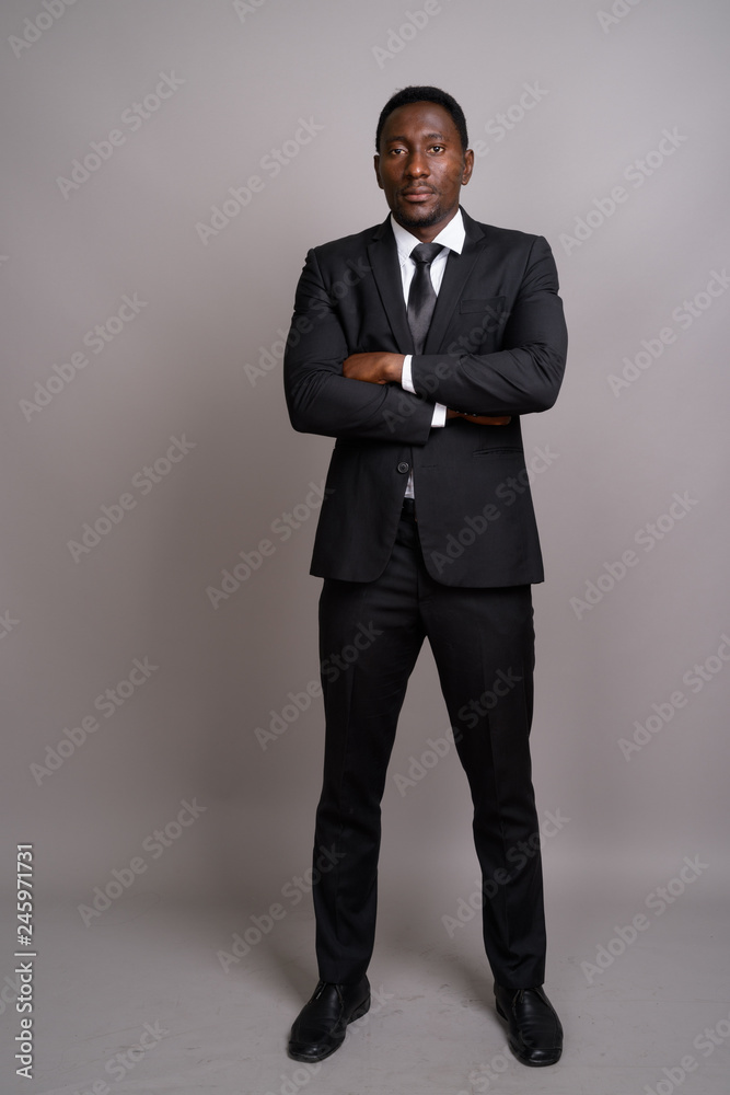 Young handsome African businessman against gray background Young handsome African businessman against gray background