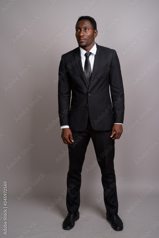 Young handsome African businessman against gray background Young handsome African businessman against gray background