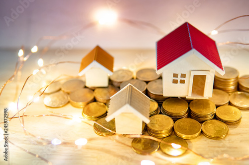 Real estate or property investment concept. Home mortgage loan rate. Gold coins stack, house models and decorative Christmas lights on the table. Saving money for future retirement.