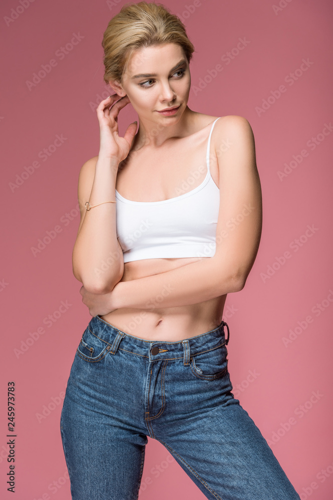 beautiful blonde woman posing in jeans and white bra, isolated on pink beautiful blonde woman posing in jeans and white bra, isolated on pink