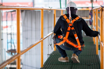 Construction worker wearing safety harness and safety line working on construction.