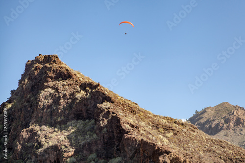  A man on a red paraglider is flying in the sky.