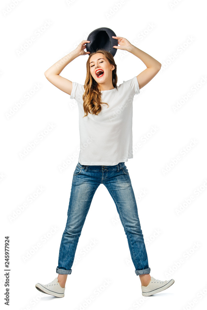 young cheerful girl in jeans, white t-shirt, sneakers holding a hat with both hands. isolated on white background young cheerful girl in jeans, white t-shirt, sneakers holding a hat with both hands. isolated on white background