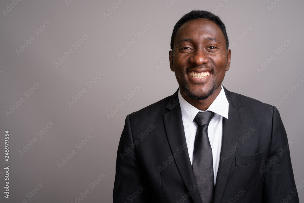 Young handsome African businessman against gray background Young handsome African businessman against gray background