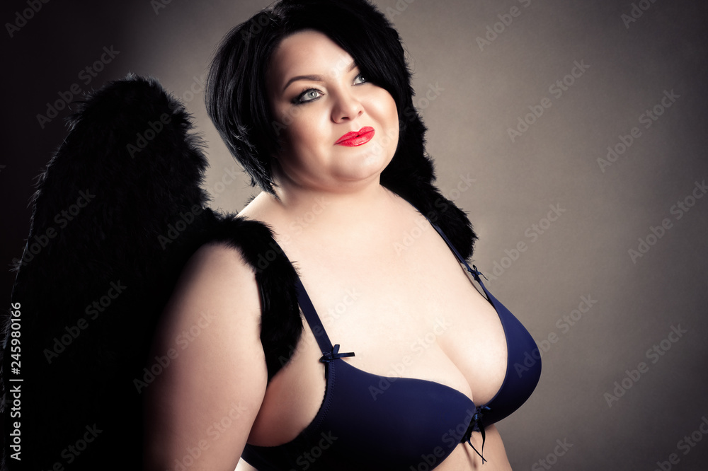 smiling beautiful fat woman with big breasts in bra with black wings Stock  Photo