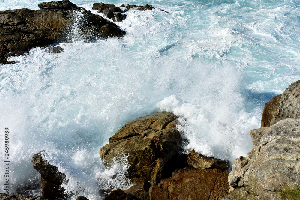 Wild waves splashing against the rocks. Blue sea with white foam, Galicia, Spain. Wild waves splashing against the rocks. Blue sea with white foam, Galicia, Spain.