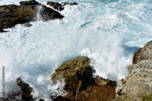 Wild waves splashing against the rocks. Blue sea with white foam  Galicia  Spain.