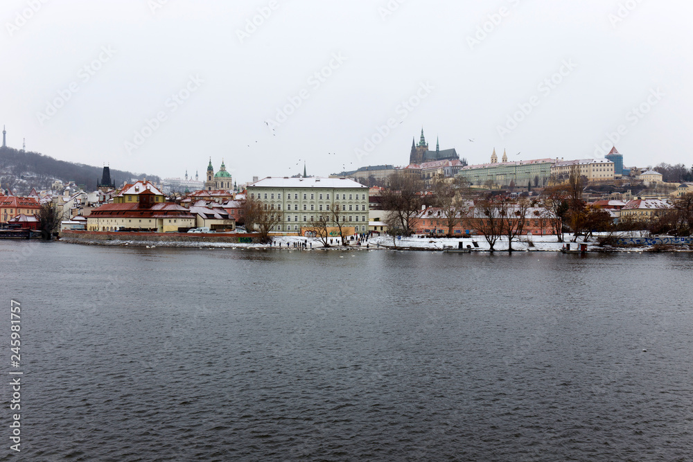 Snowy foggy Prague Lesser Town with gothic Castle above River Vltava, Czech republic