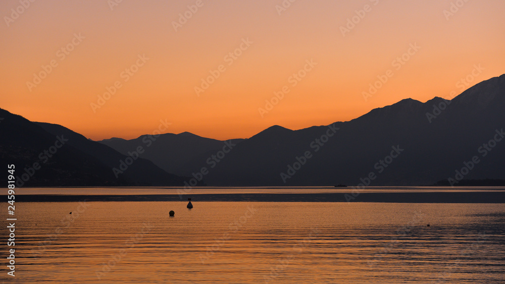 Tramonto sul lago, cielo arancione e anatre in lontananza