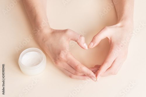 Beautiful groomed woman's hands with body and skin cream on a light background.