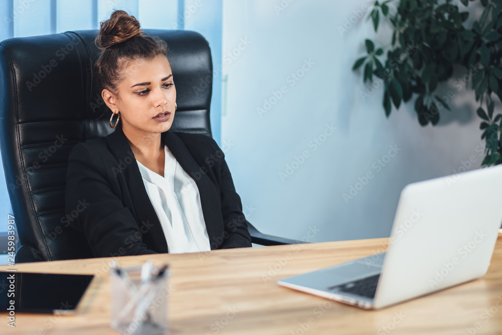 A young girl dressed in business clothes is working on a laptop. A young girl dressed in business clothes is working on a laptop.