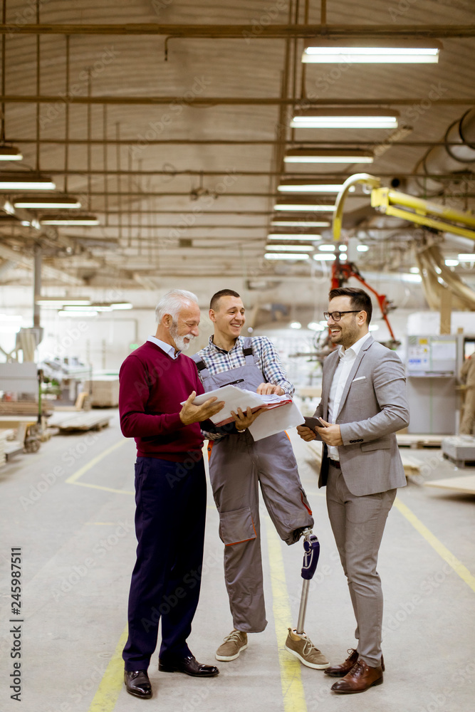 Three men standing and discuss in furniture factory Three men standing and discuss in furniture factory