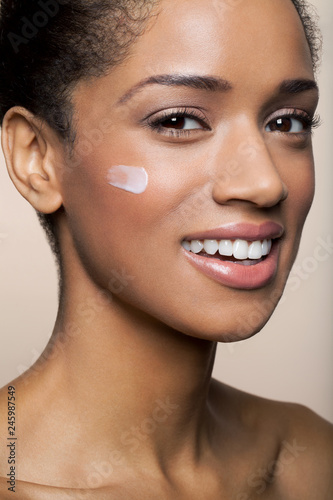 Beautiful, young, black woman with a big smile and a dab of lotion on her cheek, close up.