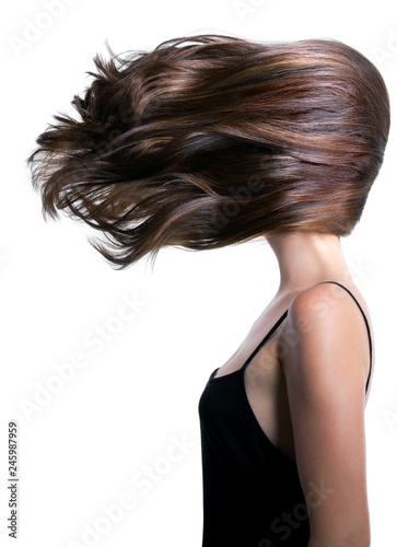 Profile of a young woman with her hair blowing sideways covering her face.