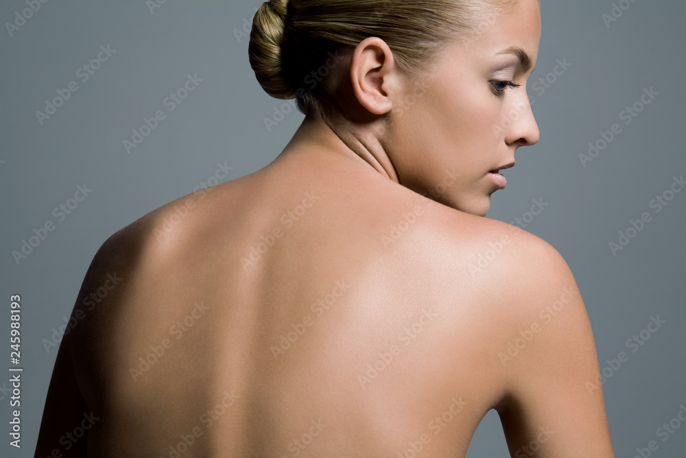 Foto de Back view of a young woman's naked upper body and her head turned  profile. do Stock