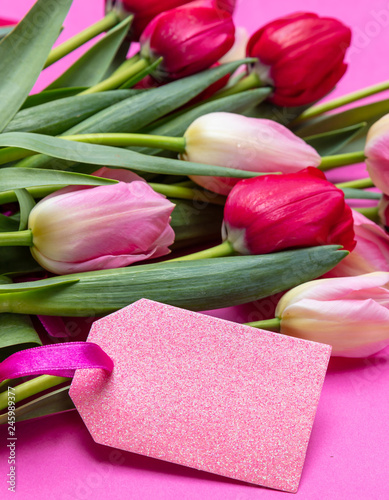 Fototapeta Naklejka Na Ścianę i Meble -  Tulips bouquet and blank tag on bright pink background, copy space, closeup view