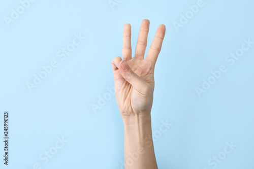 Woman showing W letter on color background, closeup. Sign language