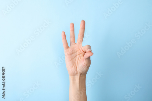 Woman showing number nine on color background, closeup. Sign language