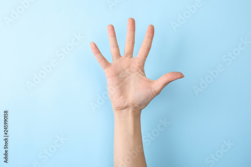 Woman showing number five on color background, closeup. Sign language photo