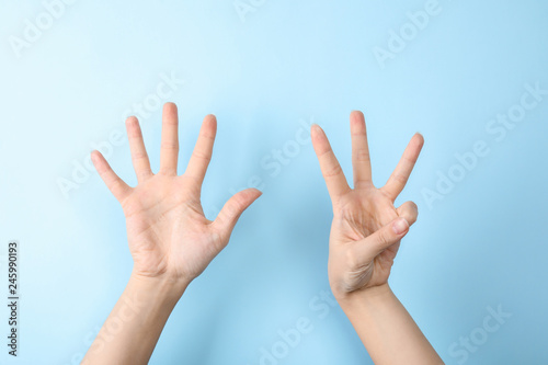Woman showing sign eight on color background, closeup. Body language