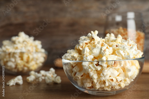 Glass bowl with tasty popcorn on table. Space for text