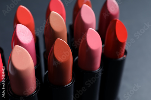 Set of different lipsticks on grey background, closeup. Cosmetic product
