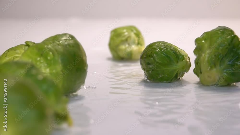 Brussels sprouts falling in water on white table in white background. Slow Motion 240 fps Brussels sprouts falling in water on white table in white background. Slow Motion 240 fps