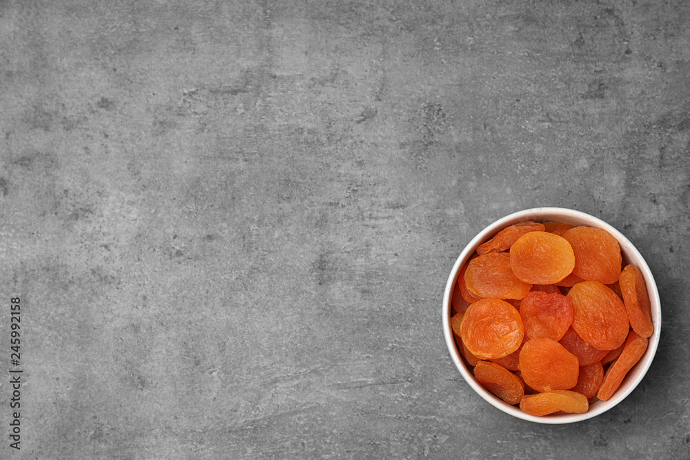 Bowl of dried apricots on grey background, top view with space for text. Healthy fruit Bowl of dried apricots on grey background, top view with space for text. Healthy fruit