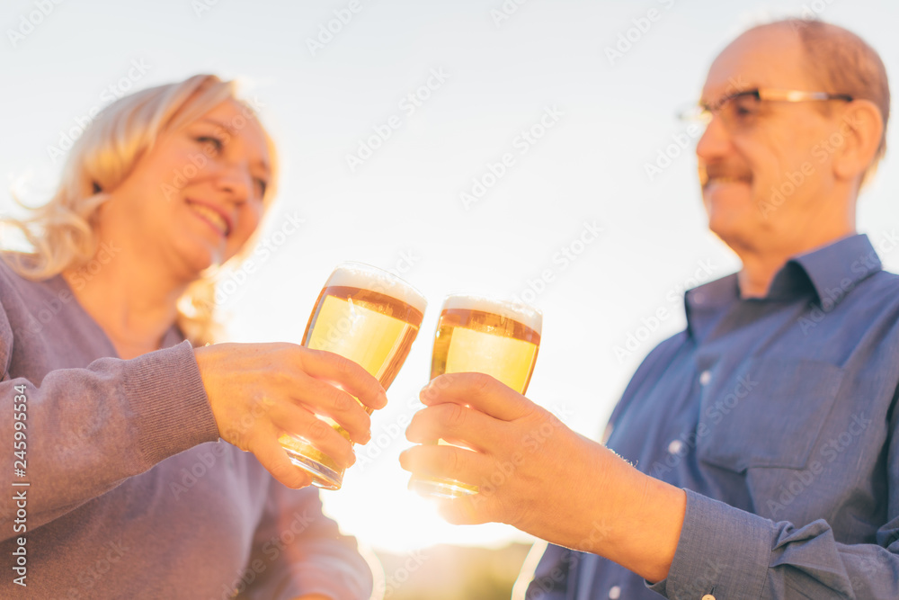 Senior couple drinking beer together, focus on hands with glasses. Senior couple drinking beer together, focus on hands with glasses.