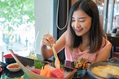 Beautiful asian woman eating sashimi, Japanese food.