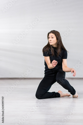 Pretty dancer on studio background. Young slim woman dancing urban street dance over grey background.