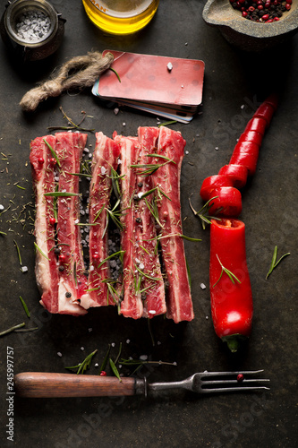 fresh raw meat with red hot pepper and old vintage fork on black stone