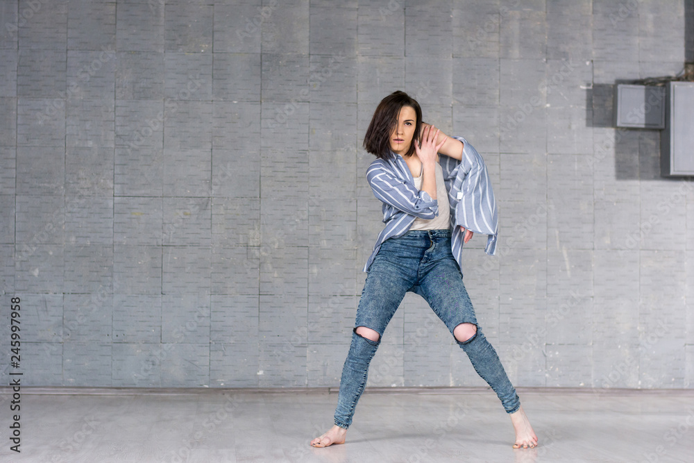 Beautiful girl dancing on studio background. Young slim girl posing on grey wall background. Female talanted dancer. Beautiful girl dancing on studio background. Young slim girl posing on grey wall background. Female talanted dancer.