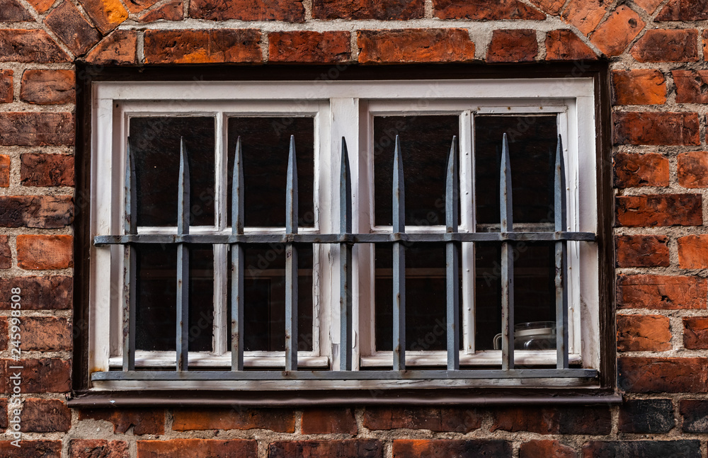 Vergittertes Fenster an einem Backsteinhaus