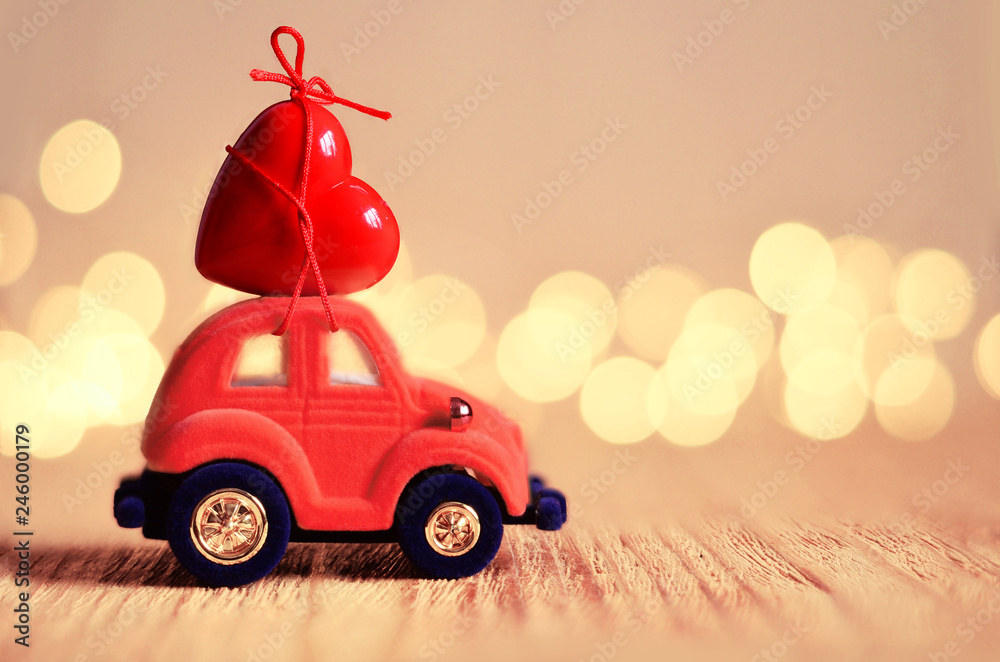 Little red car carries a heart. The concept of Valentine Day.