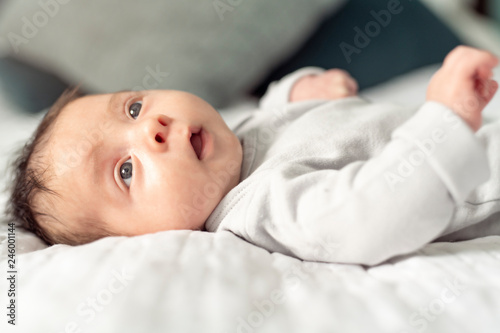 A happy newborn baby on the bed at home