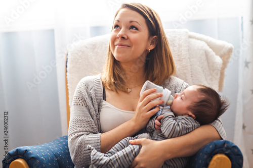 Konstfotografi Portrait of a pretty mother feeding her newborn baby from a bottle while relaxin