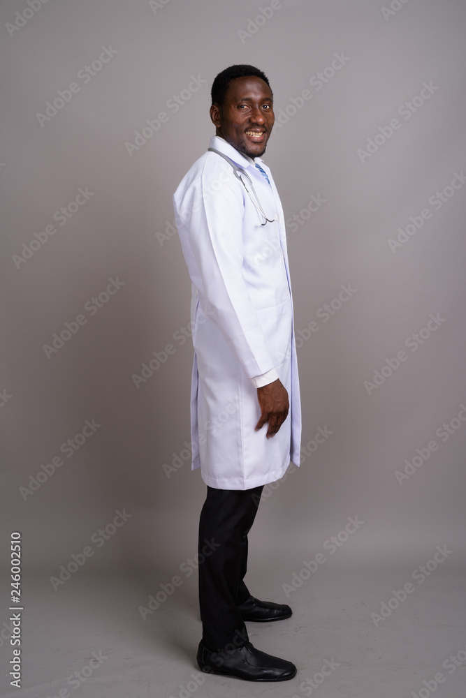 Young handsome African man doctor against gray background Young handsome African man doctor against gray background