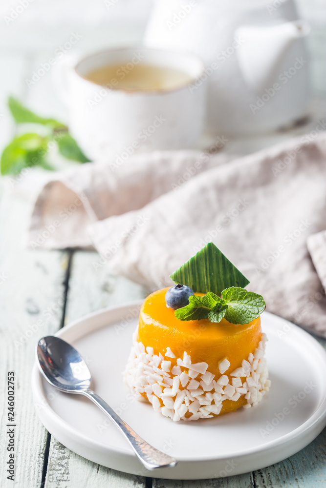 Piece of mango mousse cake on plate over white wooden table. Piece of mango mousse cake on plate over white wooden table.